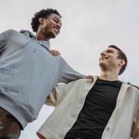 two men outside hugging and smiling at each other